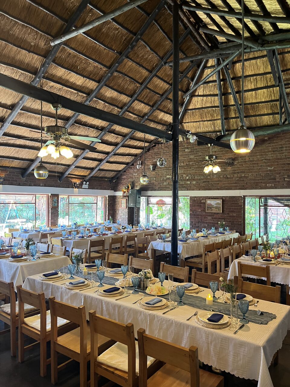 Long banquet tables dressed in blue and gold beneath a timber roof