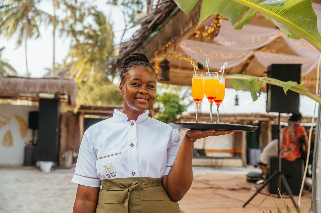 Server presenting welcome drinks at a beachside wedding reception