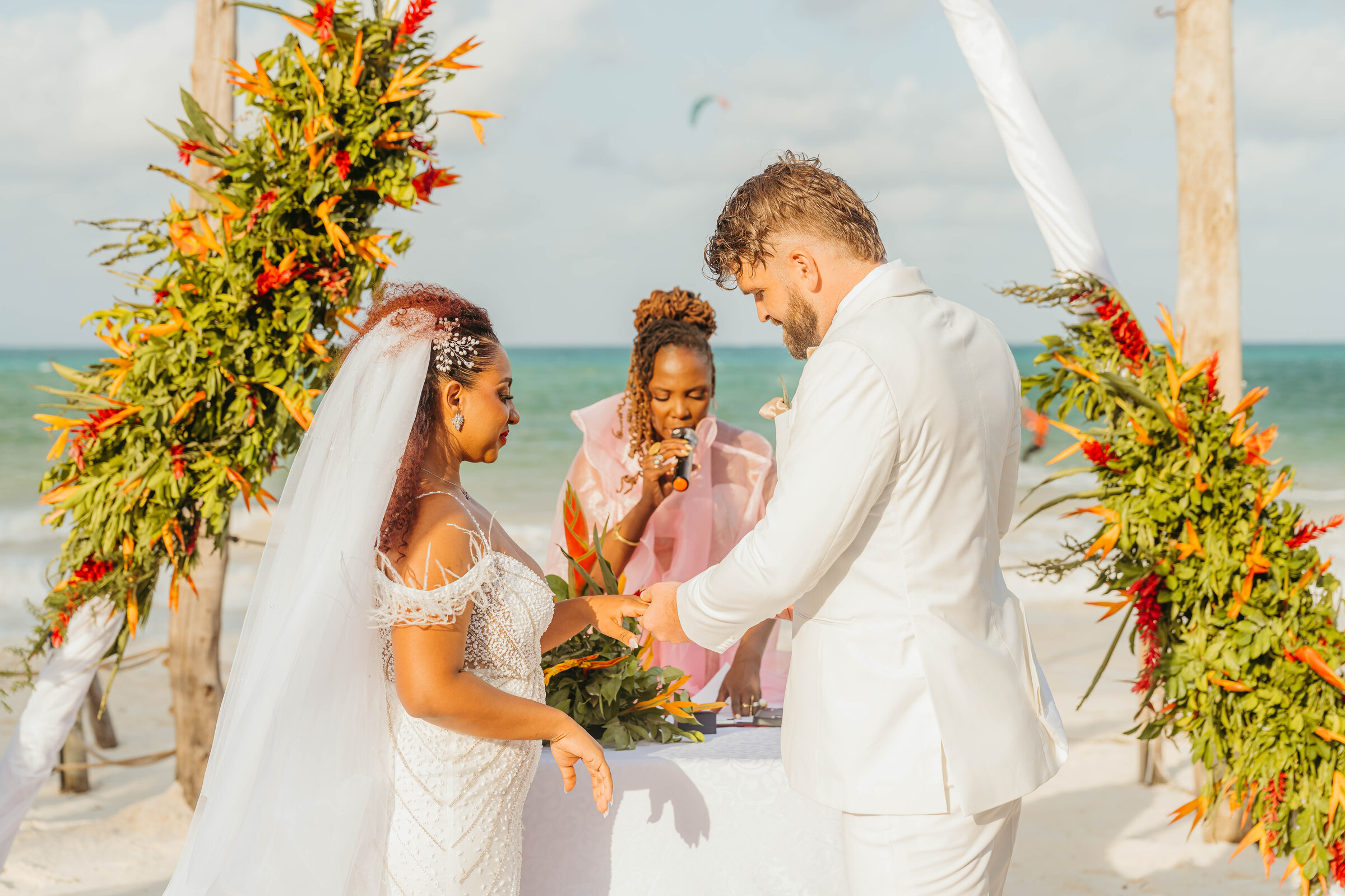 Reception guests in pastel formalwear relaxing in a thatched beach lounge