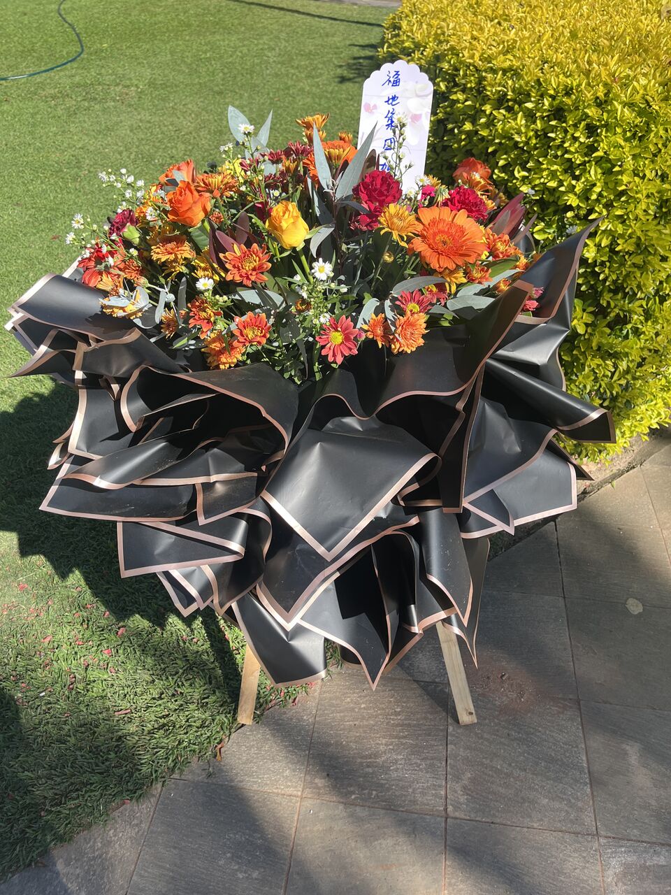 Bright arrangement of orange and yellow blooms with a sculptural ribbon