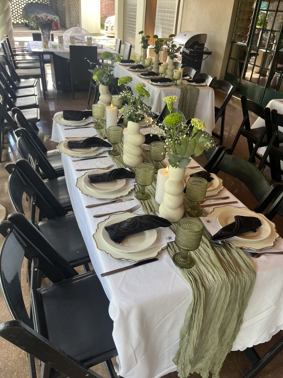 Long banquet table dressed with a greenery runner and gold cutlery